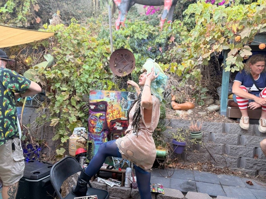 Artist with mixed-media painting in an outdoor garden studio